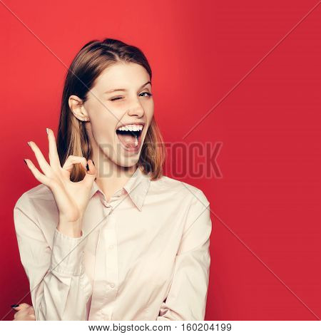 Winking Girl Shows Ok Gesture