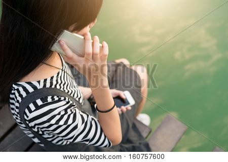 Young girl teen use smart phone in one hand to talk and other hand holding once. the new generation do not miss contact communication and lost power.