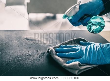 Surface sanitizing against COVID-19 outbreak. Home cleaning spraying antibacterial spray bottle disinfecting against coronavirus wearing nitrile gloves. Sanitize hospital surfaces prevention.