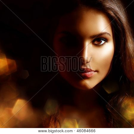 Beauty Girl Dark Portrait with Golden Sparks. Mysterious Woman Face. Darkness. Isolated on Black