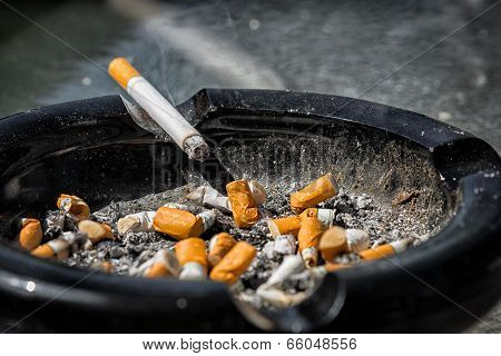 Burning Cigarette On Dirty Ashtray