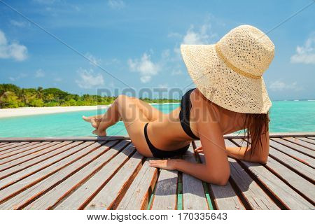 Young fashion woman relax on the beach. Happy island lifestyle. White sand, blue cloudy sky and crystal sea of tropical beach. Vacation at Paradise. Ocean beach relax, travel to Maldives islands