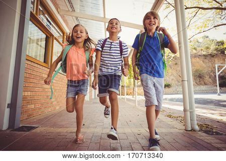 Happy school kids running in corridor at school