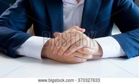 Closeup Image Of Businessman In Blue Suit Holding Ahnds On White Office Desk