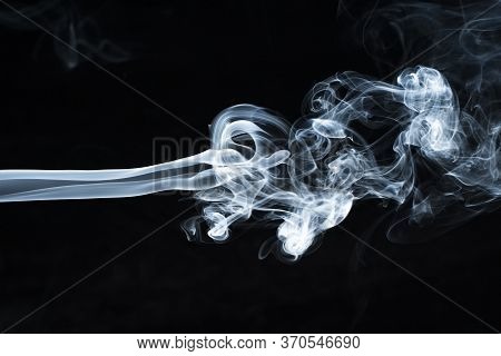 Background Image Of A Wisp Of Smoke On A Dark Background. The Texture Of The Flowing Smoke. Frozen S