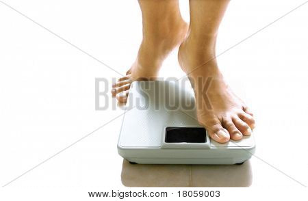 Pair of feminine feet about to stand on a weighing scale.