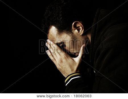 Young man buries his face in hands symbolizing depression and sadness