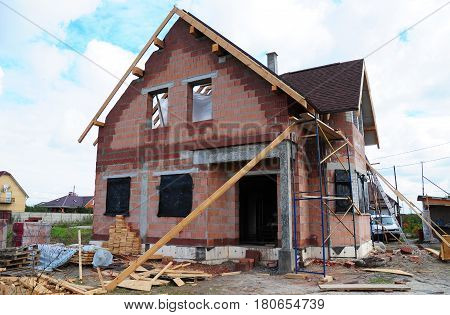 Roofing Construction and Building New Ceramic Bricks House with Modular Chimney Skylights Attic Facade and Eaves Exterior. Install Repair Asphalt Shingles or Bitumen Tiles on the Rooftop Outdoor.