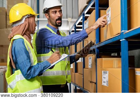 Middle east turkish white warehouse manager talk to Islam asian warehouse worker about inventory logistic route in distribution center. For business warehouse inventory and logistic concept.