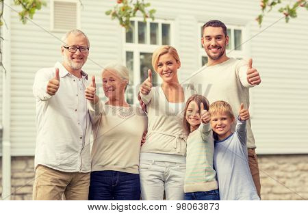 family, happiness, generation, home and people concept - happy family standing in front of house outdoors