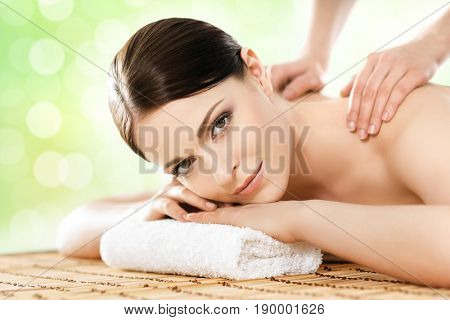 Beautiful, young and healthy woman in spa salon. Massage treatment over green summer or spring background. Traditional medicine and healing concept.