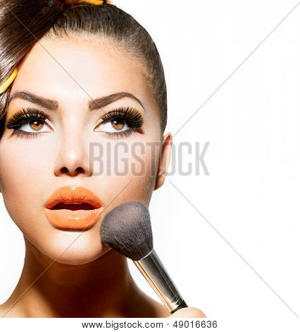 Bellezza ragazza con pennello trucco. Vacanza luminoso make-up per la donna bruna con gli occhi marroni. Orange e