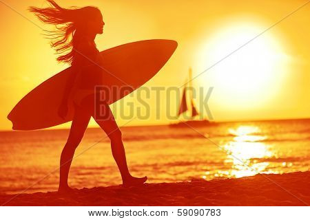 Surfing surfer woman babe beach fun at sunset. Girl walking in sunshine in warm evening sun holding surfboard. Water sport summer vacation travel concept. Kaanapali beach, Maui, Hawaii, USA