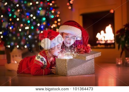 Kids Opening Christmas Presents At Fireplace