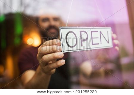 small business, people and service concept - man with open word on banner at bar or restaurant window