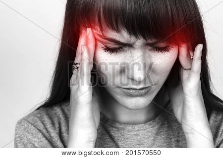 Portrait of a pretty woman over gray background stress and headache having migraine pain black and white with red accent