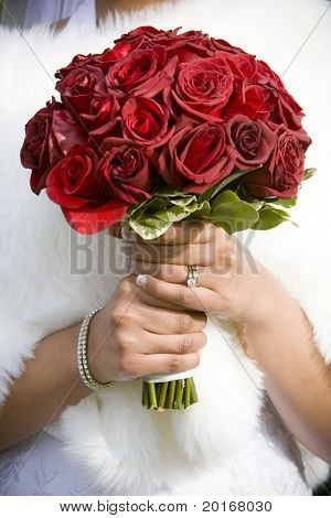 winter bride  in beautirul fur shawl holding bouquet of red roses