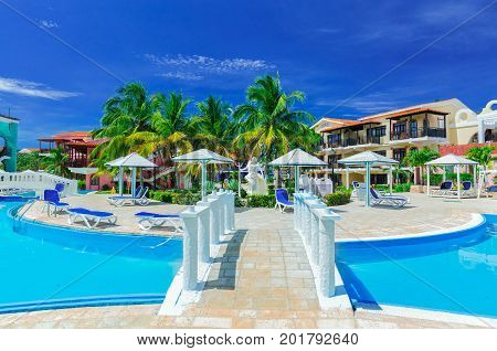 Cayo Coco island, Cuba, Colonial hotel, July 16, 2017, stunning gorgeous view of Colonial hotel grounds, beautiful inviting swimming pool and retro stylish buildings on dark deep blue sky background