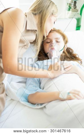 Sick Kid Girl With Oxygen Mask Laying In Bed At Hospital And Mother's Hand Holding Together And Mom 