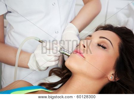 Woman getting laser face treatment in medical spa center, skin rejuvenation concept