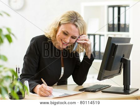 Smiling middle-aged business woman working in office