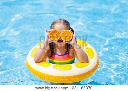 Child In Swimming Pool. Kid Eating Orange.