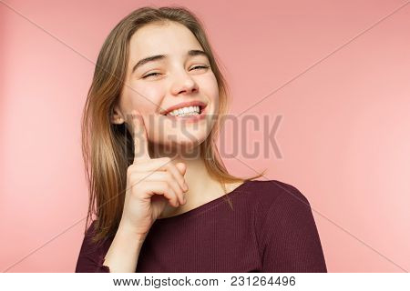 Woman Smiling With Perfect Smile And White Teeth On The Pink Studio Background And Looking At Camera