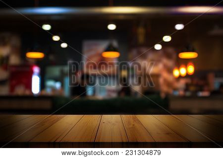 Empty Wooden Table Top With Blur Coffee Shop Or Restaurant Interior Background.