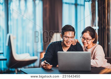 Young Asian Married Couple Working Together Using Laptop At Home Or Modern Office With Copy Space. S