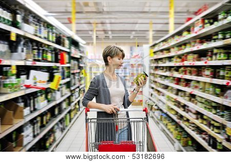 Woman Shopping And Choosing Goods At Supermarket