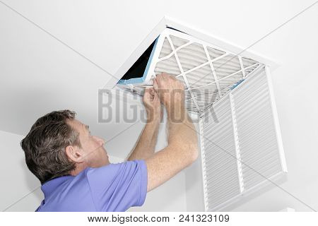 Mature Man Taking Out A Dirty Air Filter From A Home Ceiling Air Return Vent. Male Removing A Dirty 