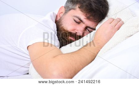 Man In Shirt Laying On Bed, White Wall On Background. Macho With Beard And Mustache Sleeping, Relaxi