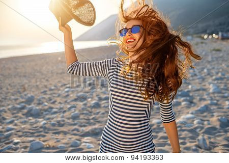 Woman in stripped dress with a hat on the beach