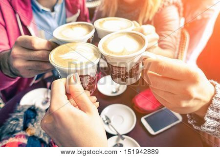 Group of friends cheers with cappuccino cup in cafe bar with phone on table - Family having fun drinking together at restauran in winter season closeup scene with soft vintage filter  