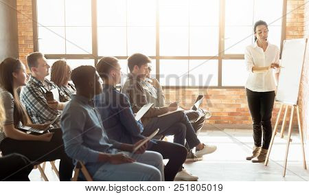 Learning Foreign Language. Cheerful Woman Teacher Near Whiteboard Explaining Rules To Group Of Stude