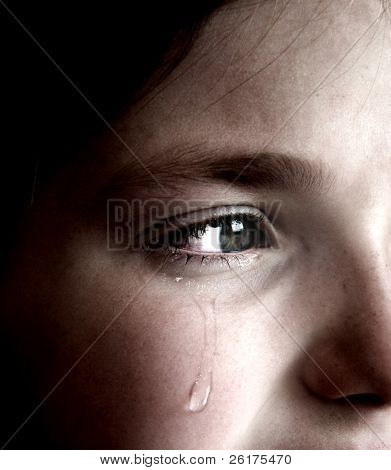 Closeup of girl crying with tear rolling down her cheek