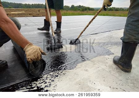 Roofer Worker Painting Bitumen Praimer At Concrete Surface By The Roller Brush Waterproofing