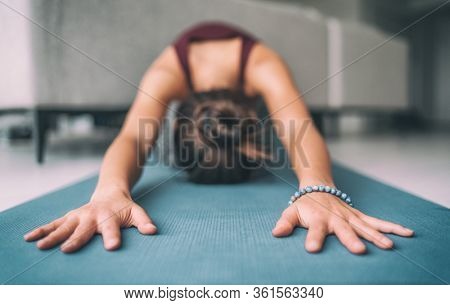 Yoga home stretching meditation woman doing childs pose warm up stretch in living room home. Hands touching floor exercise mat and mala bracelet. Fitness relaxation stress- free concept.