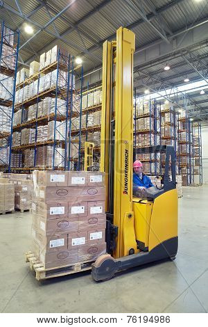 Driver Of Yellow Forklift Truck Operates, In Warehouses.