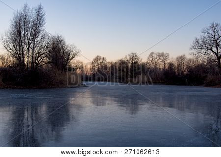 Beautiful Landscape Of Forest Lake In The Early Morning. Frozen Lake In The Forest. The Reflection O