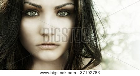 Close up photo of beautiful young woman's face with big eyes and vacant eerie stare.