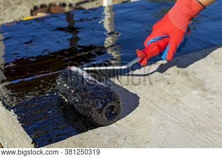 Waterproofing Coating. Workers Hand In Protective Gloves Applies Bitumen Mastic On The Foundation. R