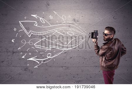 A hipster guy opening his point of view through looking a vintage camera concept with illustratied drawn arrows on urban wall