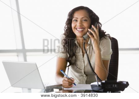 Mulher de negócios do Oriente Médio na mesa usando o Laptop e telefone