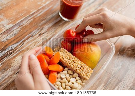 healthy eating, dieting and people concept - close up of woman hands with food in plastic container and fresh tomato juice at home kitchen