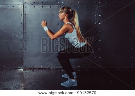 Athletic young woman fitness model warming up doing squats exercise for the buttocks concept sport s