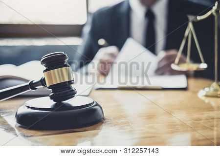 Male Lawyer Or Judge Working With Contract Papers, Law Book And Wooden Gavel On Table In Courtroom, 