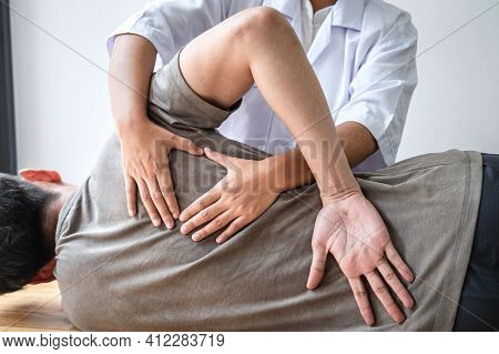 Doctor Or Physiotherapist Working Examining Treating Injured Back Of Athlete Male Patient, Doing The