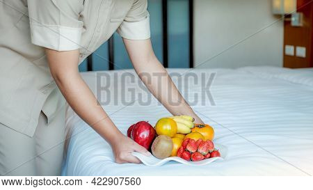 Hotel Maid Hand Holding Fruits Tary  In To The Luxury Hotel Bed Room Ready For Tourist Travel.