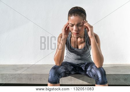 Athlete fitness running woman with headache migraine pain during cardio workout run. Asian athlete with health problem feeling exhausted during difficult strength training exercise at gym.